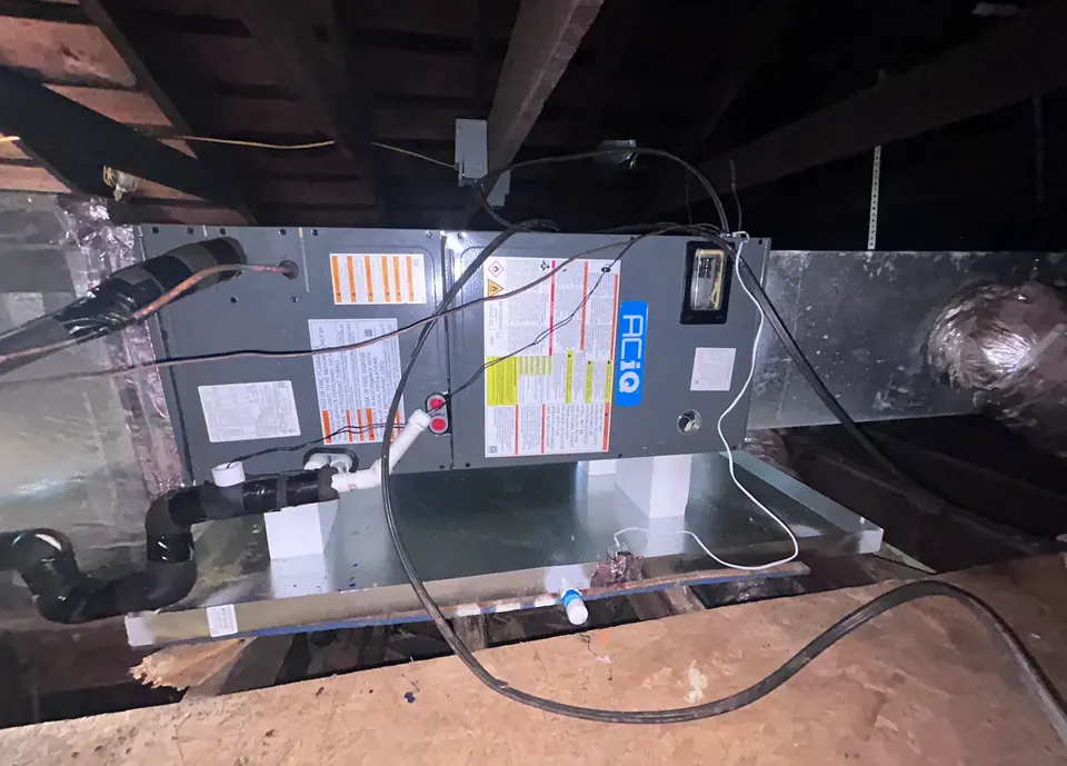 ACiQ air handler installed in a dark Kenner attic with silver flex ductwork and PVC condensate drain line
